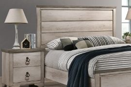 Whitewash nightstand with lamp beside a bed